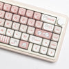 A close-up view of a light pink mechanical keyboard featuring custom white and pink dye-sublimated PBT keycaps.
