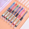 A set of precision rollerball gel pens in various colors laid out on a light pink background.