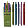 A set of five green and purple gel ink pens with soft grips displayed against a white background.
