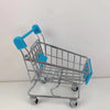 A silver mini shopping cart desktop organizer with blue handles and rolling wheels.
