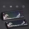 A close-up view of a black mechanical keyboard featuring translucent Ukiyo-e style keycaps and various material options.