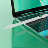 Ein weißer Stift liegt auf einer grünen Laptop-Tastatur mit hellem Bildschirm im Hintergrund.