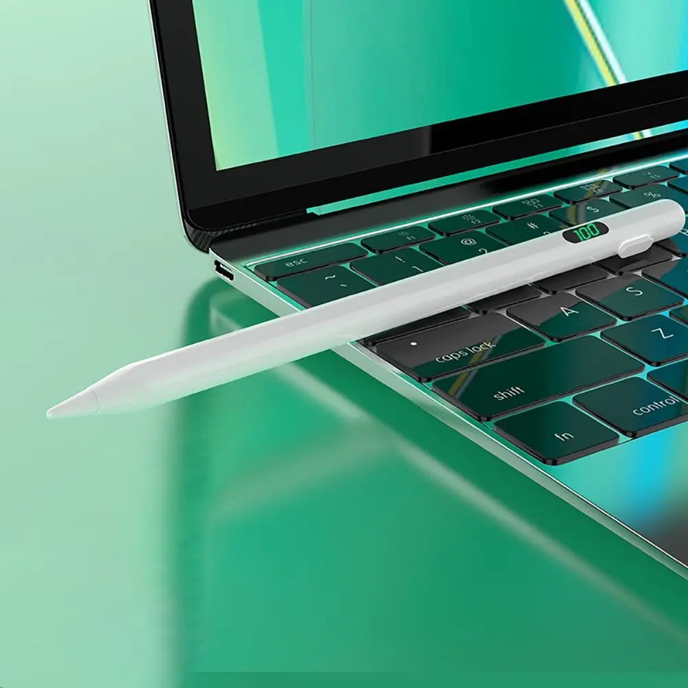 Ein weißer Stift liegt auf einer grünen Laptop-Tastatur mit hellem Bildschirm im Hintergrund.