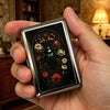 A hand holds a vintage stainless steel card and cash case featuring an ornate floral design.