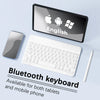 Eine weiße Bluetooth-Tastatur neben einem Tablet und einem Smartphone, die Kompatibilität mit mobilen Geräten veranschaulicht