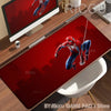 A red Spider-Man graphic desk mat featuring a superhero in a dynamic pose on a wooden desk.