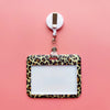 A leopard print ID holder is clipped to a white lanyard against a pink background.