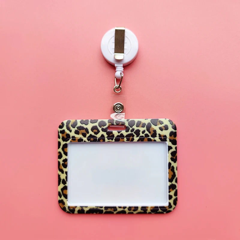 A leopard print ID holder is clipped to a white lanyard against a pink background.