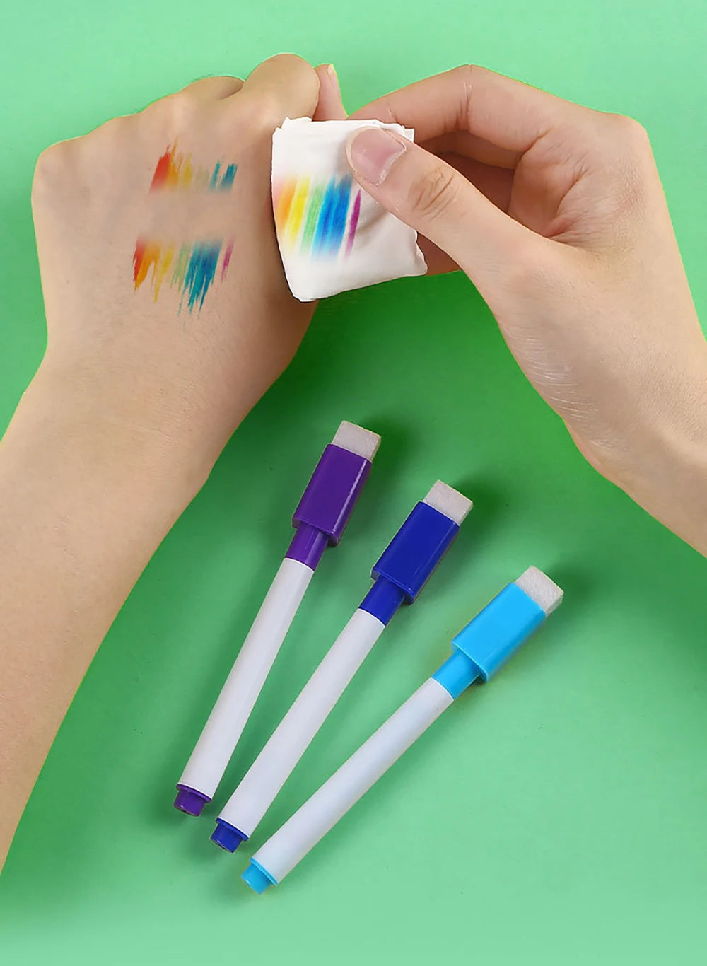 A hand holds a white cloth with colorful paint marks, next to an 8-pack of magnetic whiteboard pens.