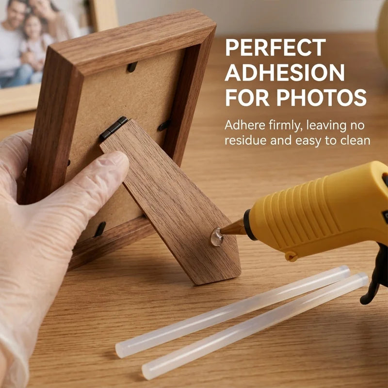 A hand applies hot melt glue sticks to a wooden photo frame for adhesion.