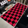 A red and black checkered desk mat is placed on a wooden desk next to a keyboard and a gaming controller.