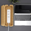 A handwoven rattan cable management box with a lid next to a silver USB cable and a laptop.