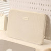 A beige laptop sleeve with a smooth texture and a small embossed logo is displayed against a white background.