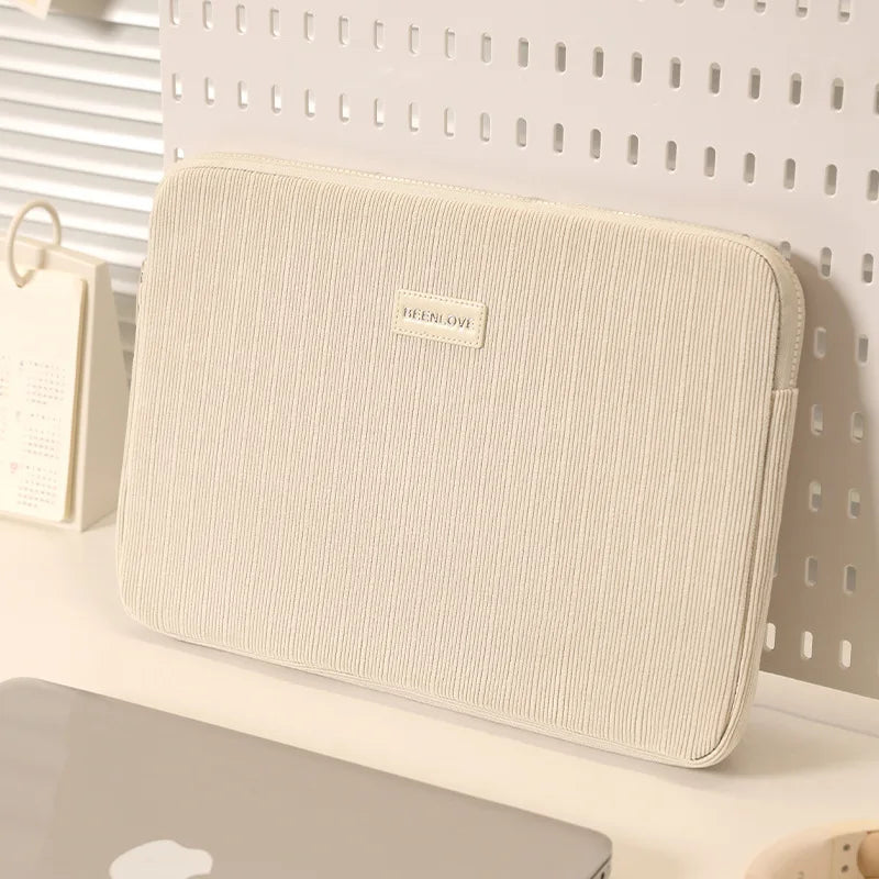 A beige laptop sleeve with a smooth texture and a small embossed logo is displayed against a white background.
