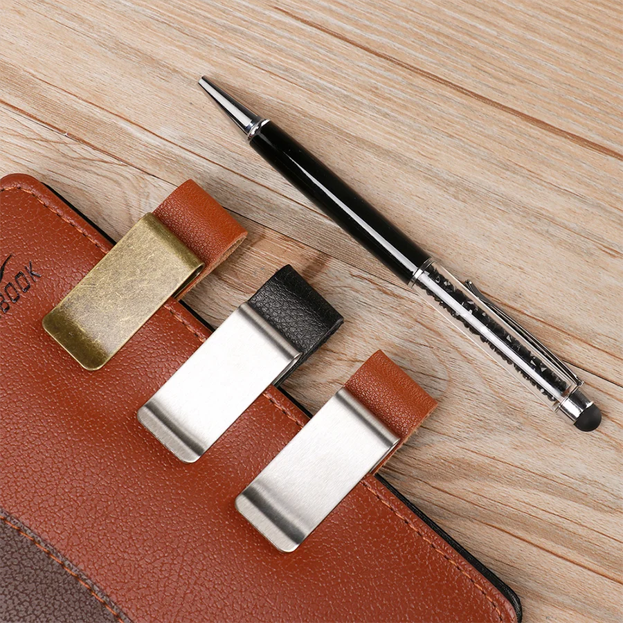 A brown leather pen holder with a brass clip and a black pen resting on a wooden surface.