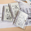 A set of three transparent binders showing monthly savings challenges for 5K, 10K, and 25K goals.