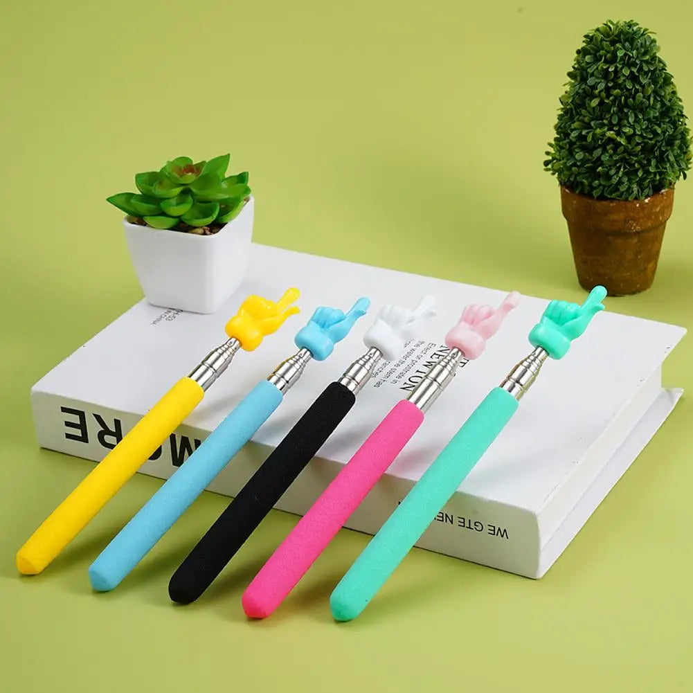 A set of colorful retractable hand pointer sticks in yellow, blue, black, pink, and teal resting on a white book with a potte