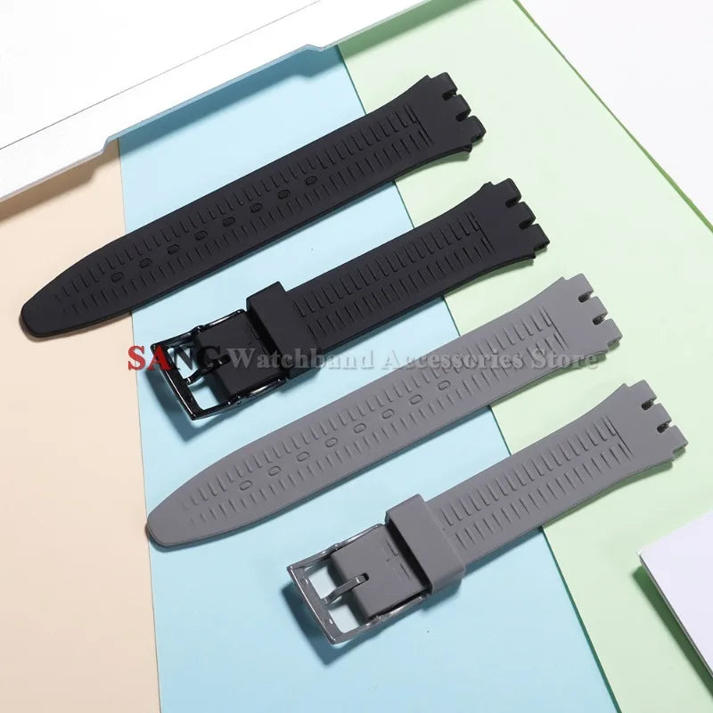 A black silicone watch strap is shown alongside replacement tools on a light blue background.