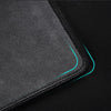 A close-up view of a gray overlocked mouse pad with a teal trim on a dark surface.