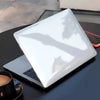 Una funda protectora blanca para un MacBook Pro sobre una superficie oscura.