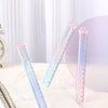 A set of three clear glass rulers shaped like cat paws with a gradient color, resting on an open notebook.