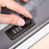A hand is adjusting a black knob on a small electronic device, likely a mini secret cash storage box.