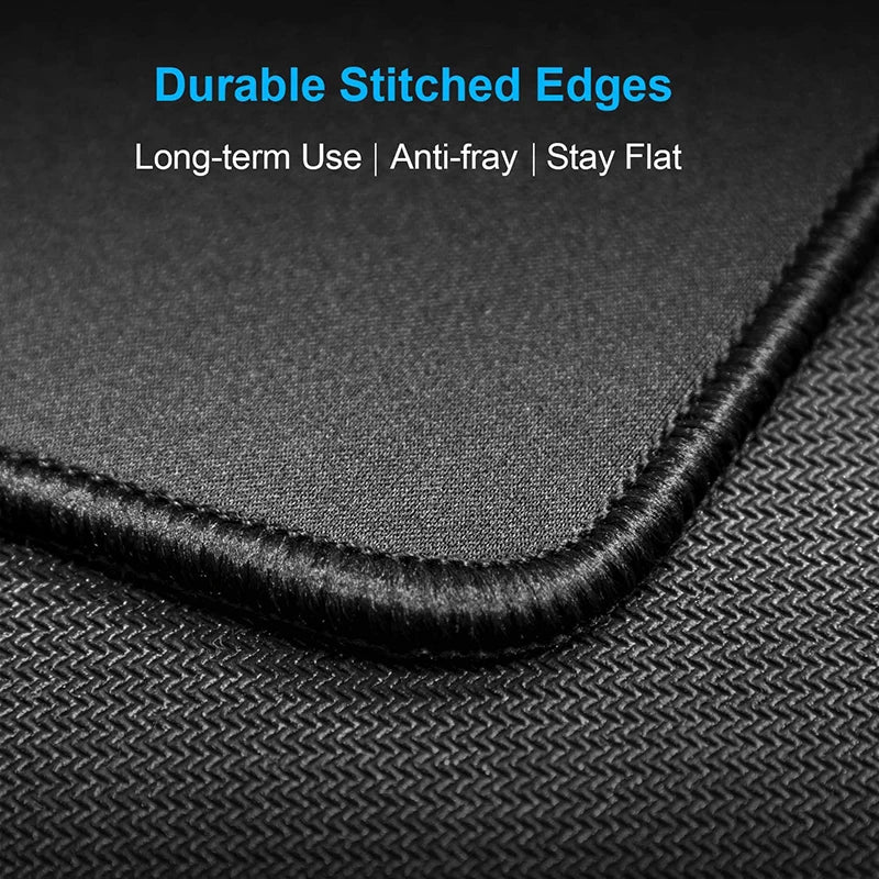 Black stitched edge of a large contoured rubber mouse pad shown against a textured black surface.