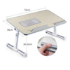 A portable adjustable laptop desk stand with a light wood-colored surface and silver metal supports.