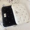 A white padded laptop sleeve case with quilted texture and black dots is shown next to a black version.
