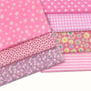 A stack of pink cotton patchwork fabric squares featuring various patterns including polka dots, gingham, and floral prints.