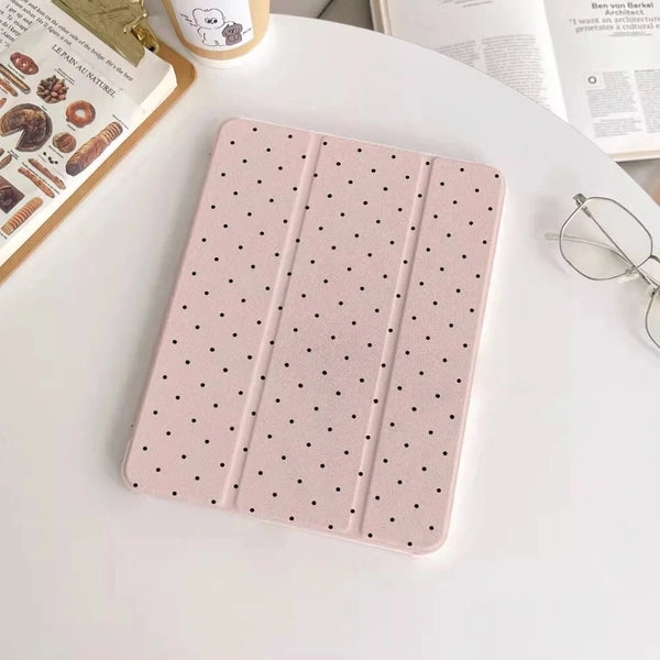 Pinkes Acryl-Schutz-Skin mit kleinen schwarzen Punkten auf weißem Tisch neben iPad-Hülle und Brille.