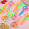 A collection of colorful two-tone plastic scissors in various shades of green, pink, and orange, displayed on a light backgro