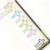 A close-up of a page from a book showing colorful cross-shaped metal paper clips used as decorative elements.