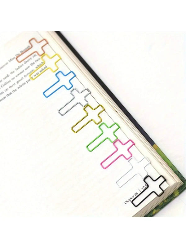 A close-up of a page from a book showing colorful cross-shaped metal paper clips used as decorative elements.