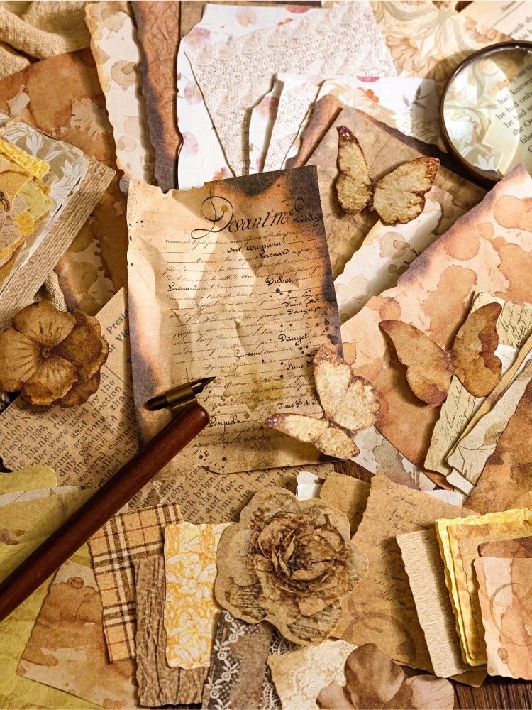 A collection of vintage paper, including aged parchment, textured cardstock, and dried flowers, used for crafting.