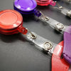 A close-up of a retractable ID card holder with various colored badge cases attached to clear plastic reels.