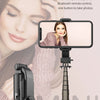 A close-up of a mini selfie stick with an LED fill light mounted on a tripod stand, shown next to a smartphone.