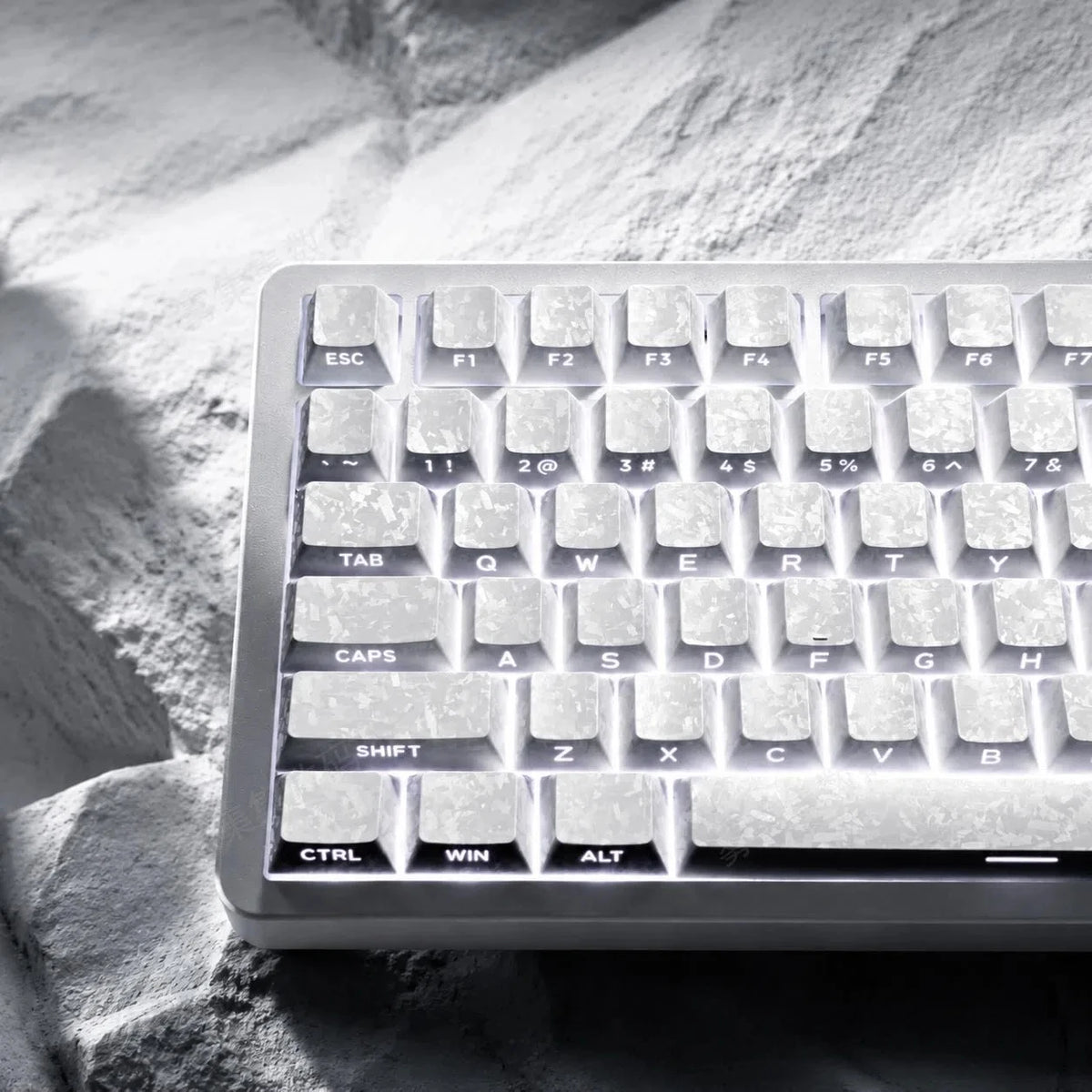 Nahaufnahme einer hellgrauen mechanischen Tastatur mit Kohlenstoffmuster-Tasten auf einer strukturierten Oberfläche.