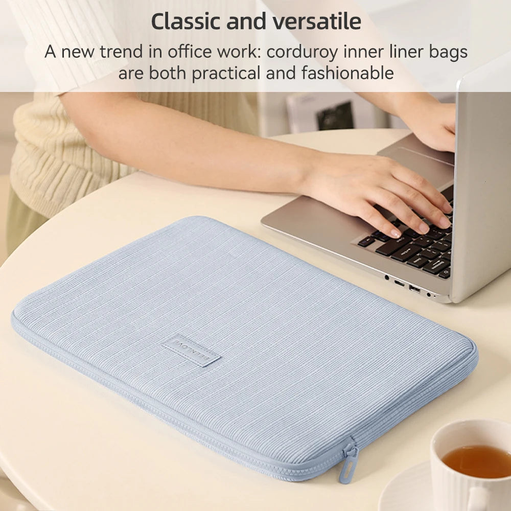A light blue striped laptop sleeve is shown on a table next to a laptop and a cup.
