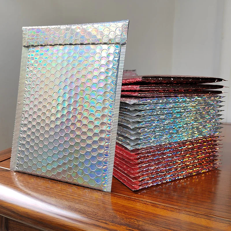 A stack of rainbow foil bubble mailers in various colors, including iridescent and metallic shades.
