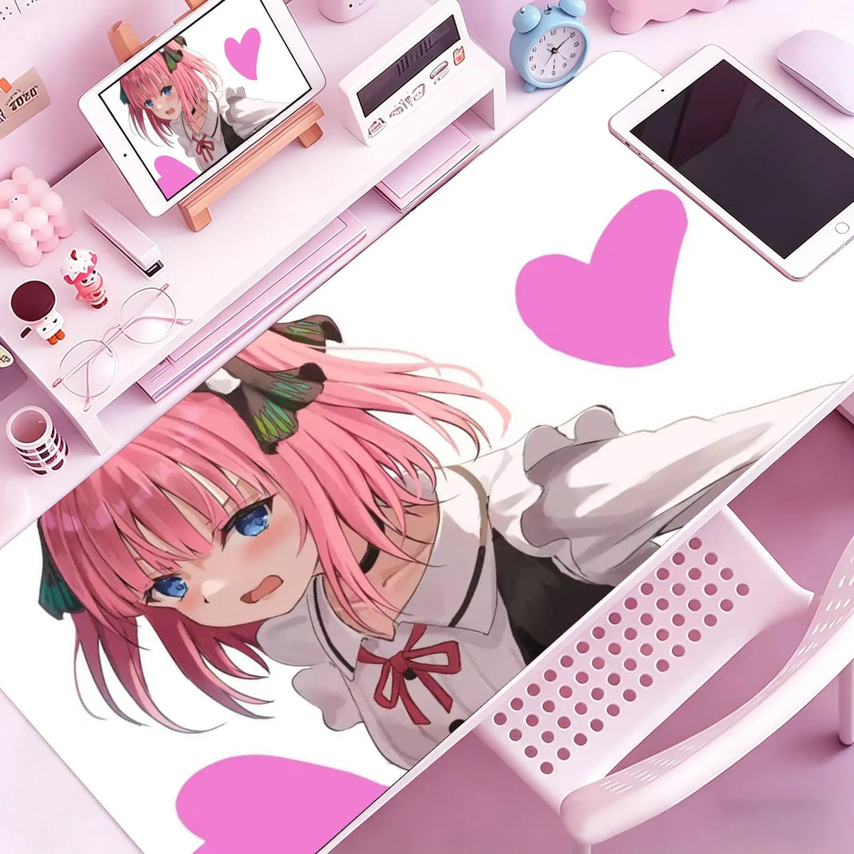 A vibrant illustration of an anime girl with pink hair and blue eyes is displayed on a white mouse pad next to various desk a