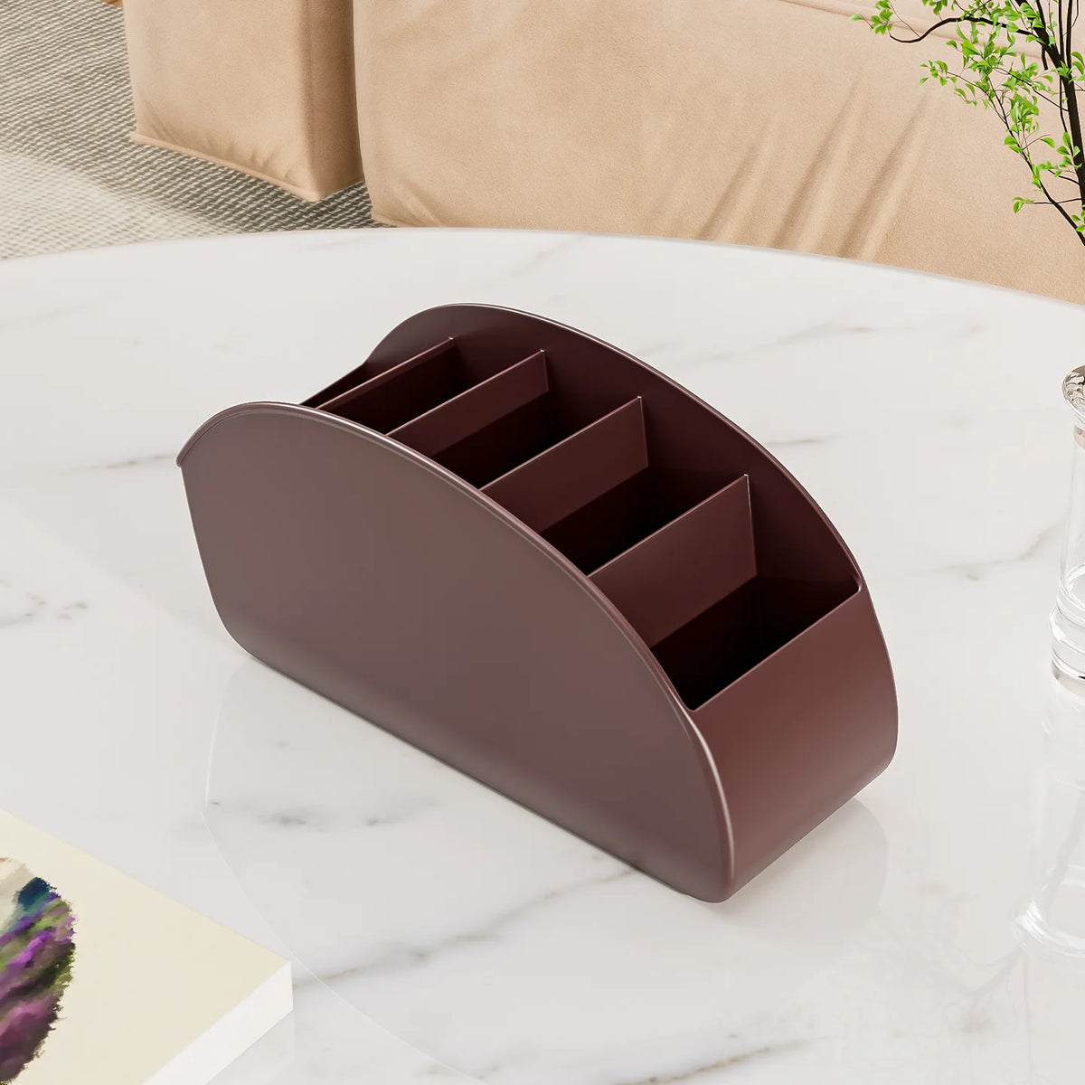A dark brown remote control holder and desk organizer tray with multiple slots resting on a white marble surface.