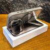 A gray magnetic shockproof phone case for an iPhone is displayed in its packaging on a wooden surface.