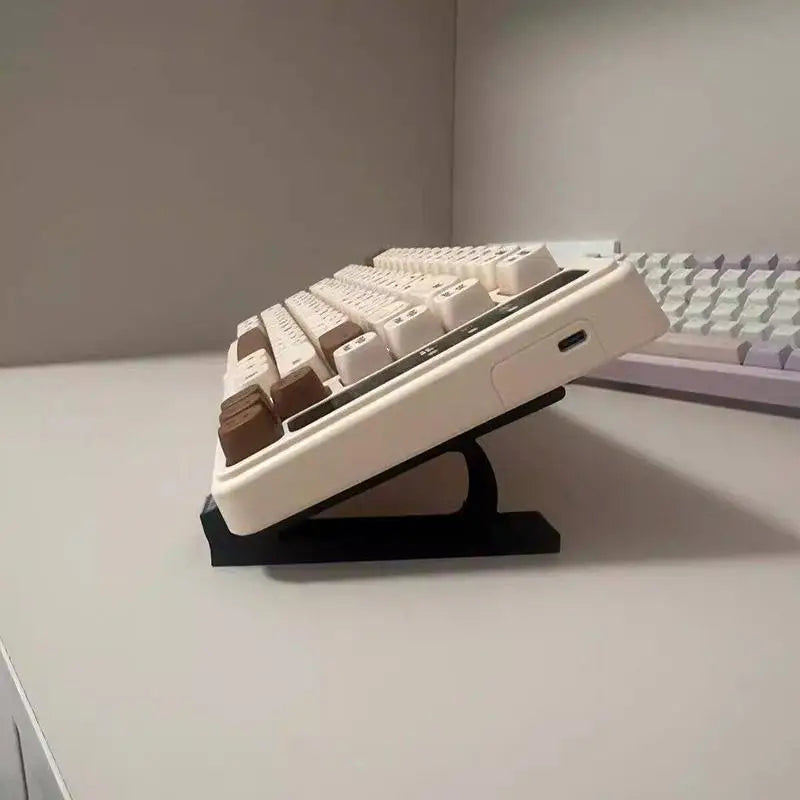 A white ergonomic keyboard height adjuster stand with multiple keyboard keys visible on the adjustable platform.