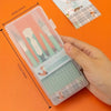Eine Hand hält eine klare Plastikverpackung mit einem Set präziser Kunstwerkzeuge zum Basteln und Scrapbooking.