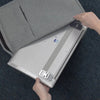 A hand is adjusting a silver portable aluminum alloy laptop stand on a dark blue fabric surface.