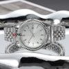 A polished stainless steel watch with a silver dial and bracelet is displayed on a reflective surface.