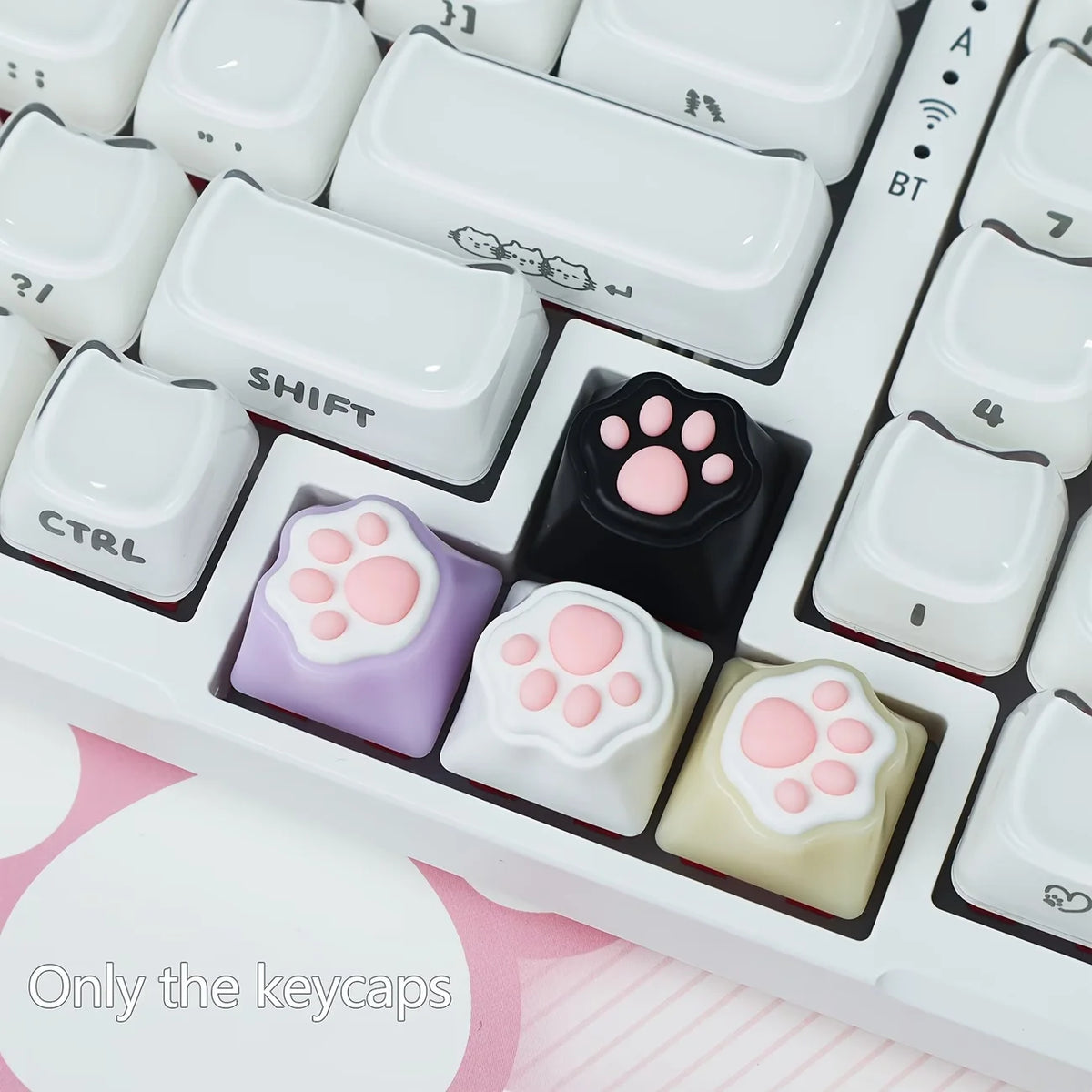 A close-up view of white mechanical keyboard keycaps featuring kawaii cat paw and pink heart designs.