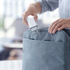 A hand is placing a white charging cable into a gray fabric pouch for easy portability.