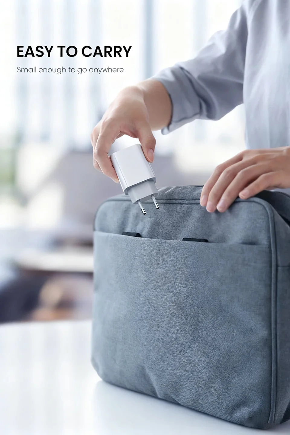 A hand is placing a white charging cable into a gray fabric pouch for easy portability.